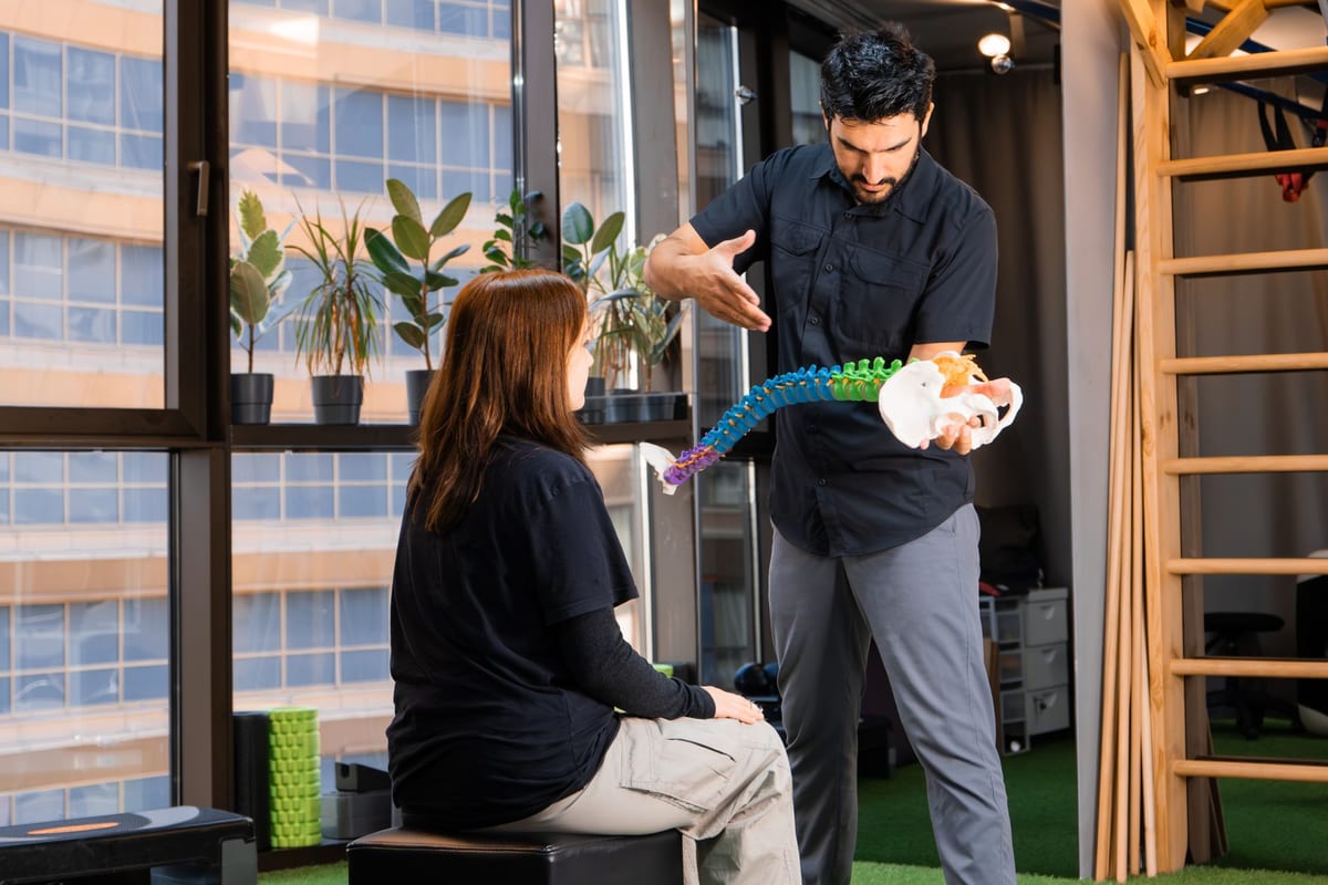 A chiropractor explaining spinal alignment with a model of the spine